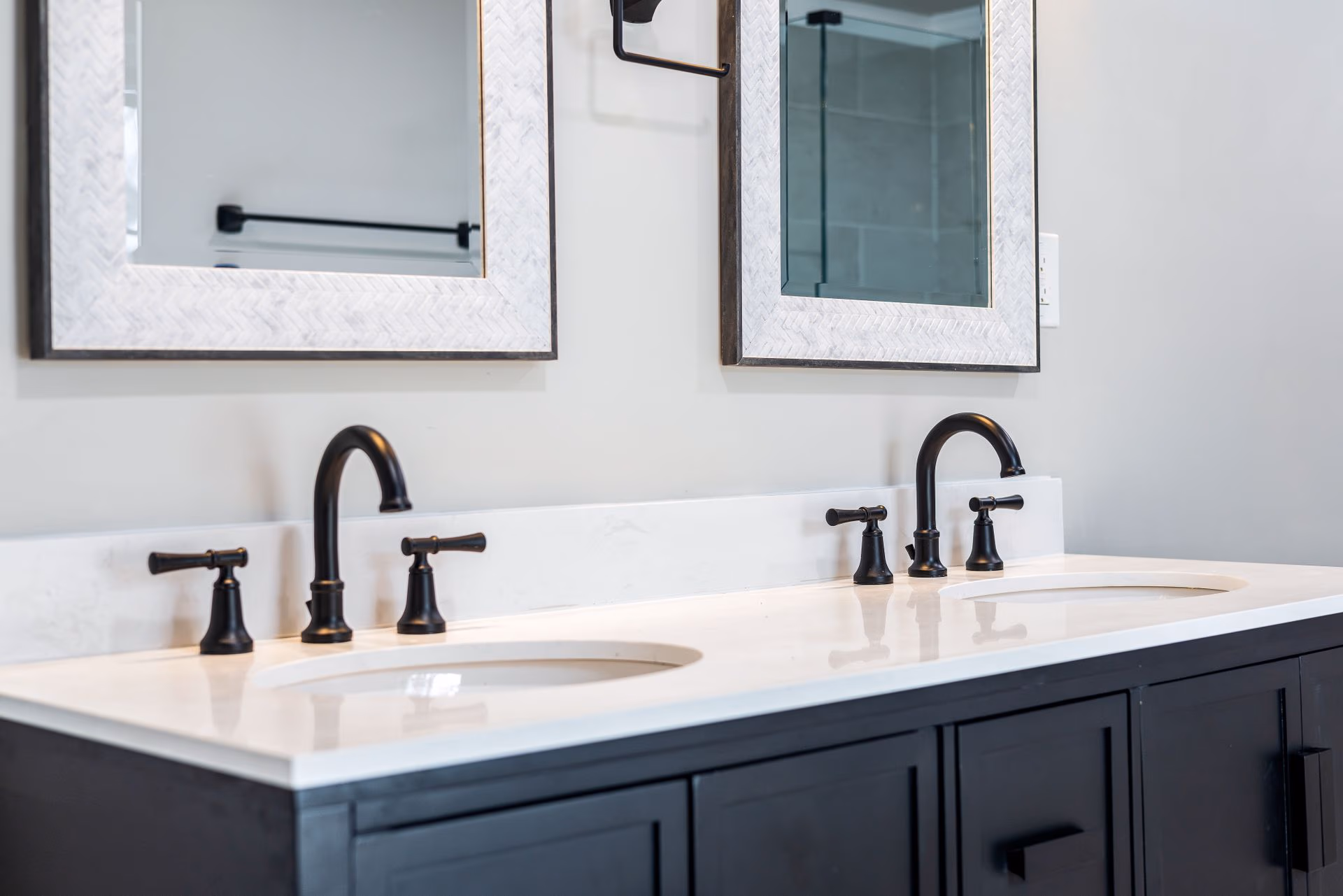 Modern double bathroom sink with black faucets under two rectangular framed mirrors.