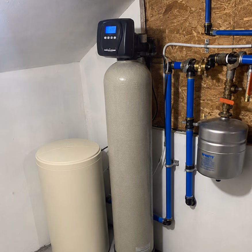 Water softener system with digital control, beige brine tank, and attached blue plumbing pipes.